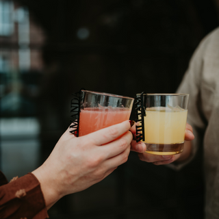 Two hands holding glasses of pink and orange drinks with custom flute tags