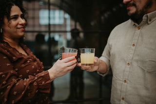 Two people holding drinks together in a dimly lit setting