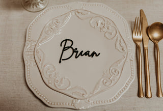 Decorative place setting with a name card labeled 'Brian' on a beige tablecloth.
