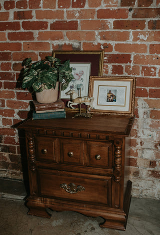 Wooden cabinet with decorative items against a brick wall