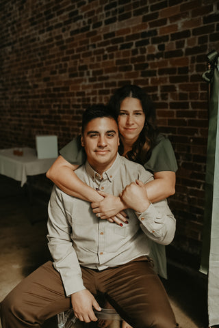 Man and woman sitting together against a brick wall.
